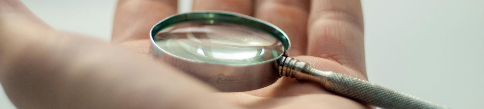 Hand holding a magnifying glass